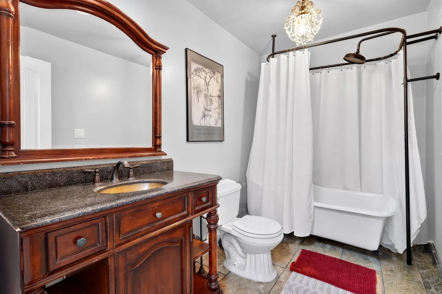 Bathroom with a dark wood vanity, toilet, and clawfoot-style tub surrounded by white shower curtains.