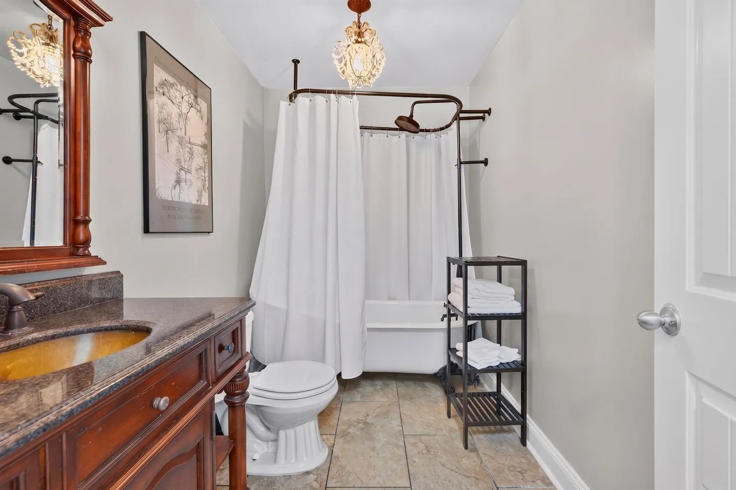Bathroom with a clawfoot bathtub, shower curtain surround, toilet, and dark wood vanity with granite countertop.