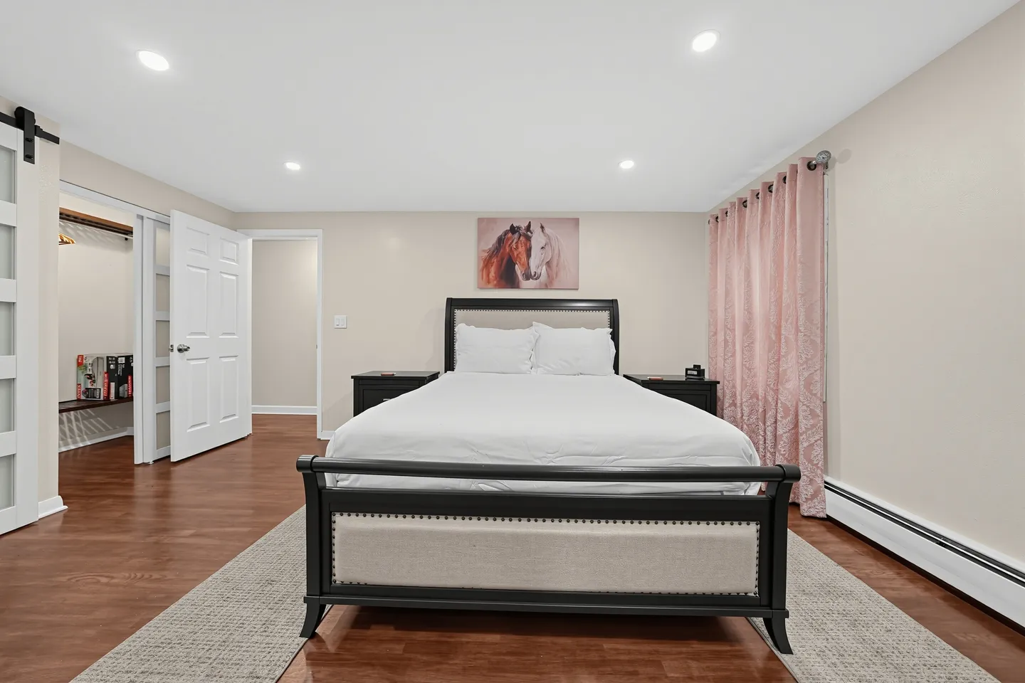 Bedroom with a dark wood bed frame, white bedding, recessed ceiling lights, and wood flooring.