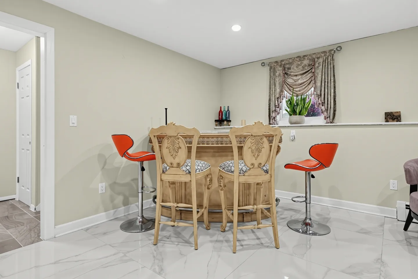 A home bar with four barstools situated on a polished marble-look tile floor.