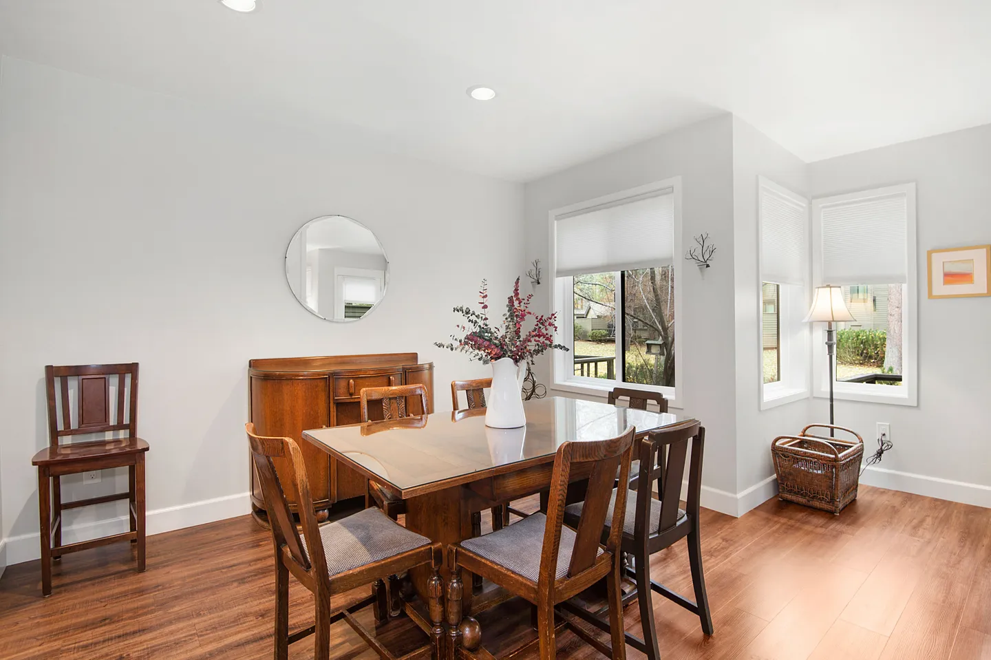 Dining area with wood dining table and chairs, a wooden sideboard, and windows letting in daylight.