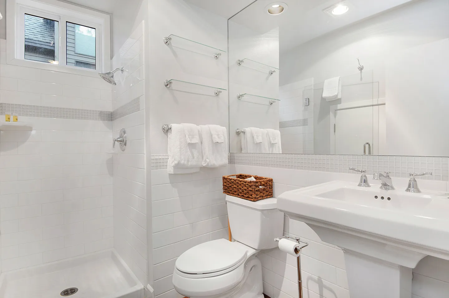 Bathroom with white subway tile, a walk-in shower, a pedestal sink, and a toilet.