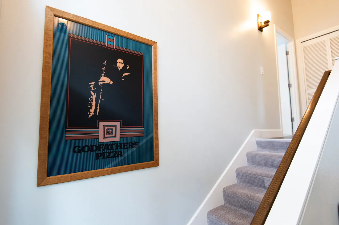 Framed Godfather's Pizza poster hung on a staircase wall leading upstairs.