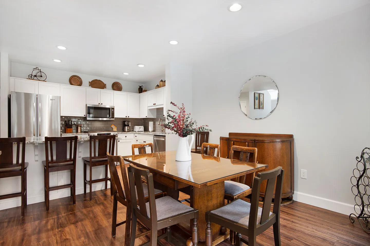 Dining area with a wooden table and chairs, adjacent to a kitchen with white cabinetry and stainless steel appliances.
