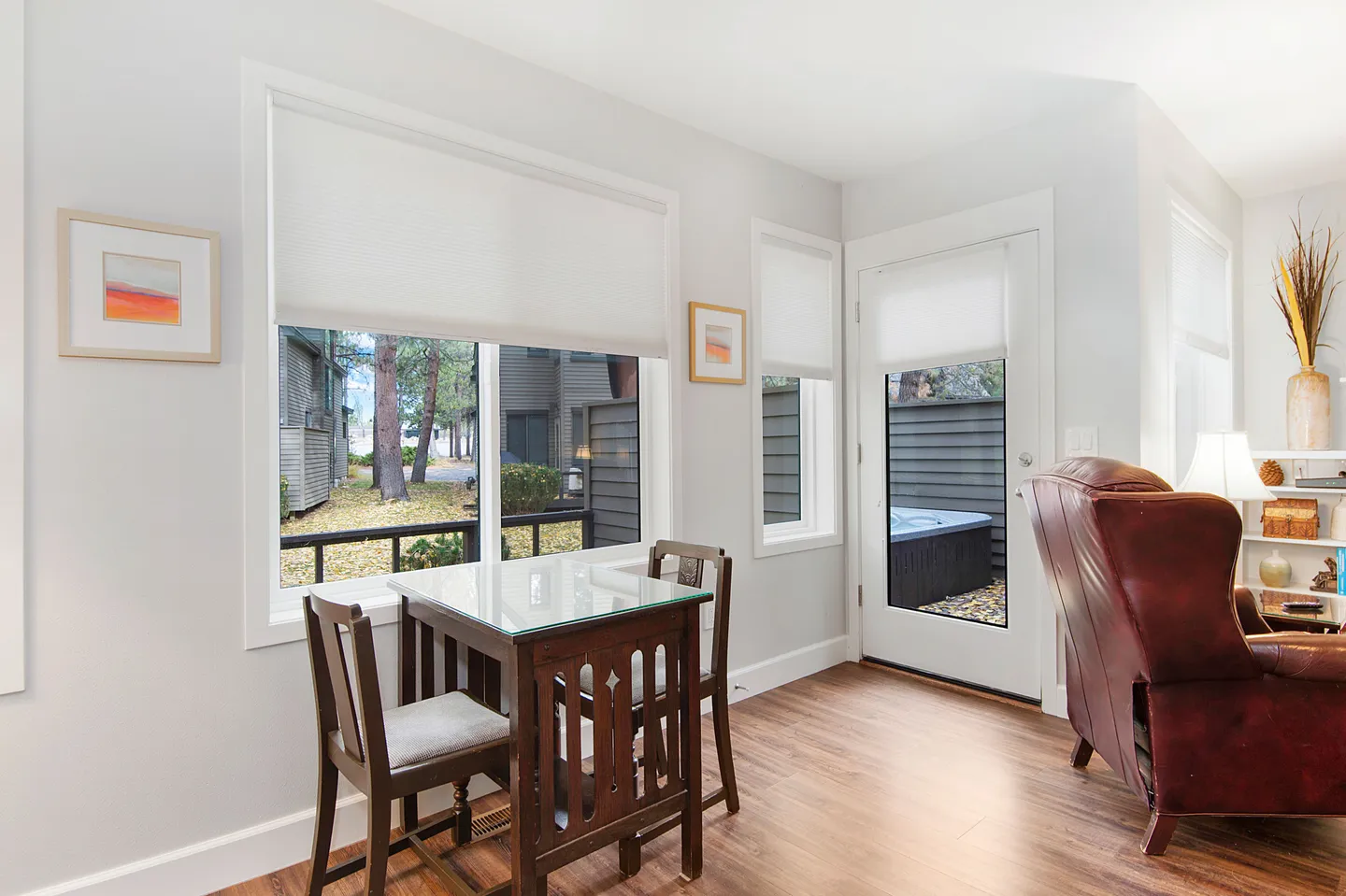 Dining nook with a small table and two chairs next to windows and an exterior door leading to a patio with a hot tub.