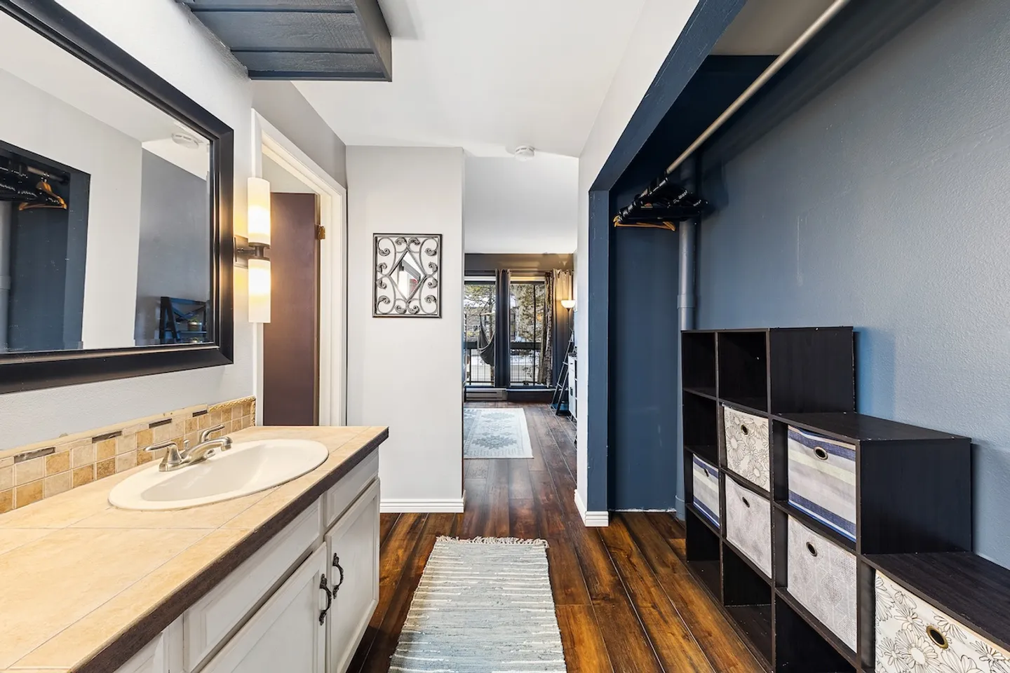 Bathroom vanity area leading down a hallway toward a brightly lit room with a patio door.