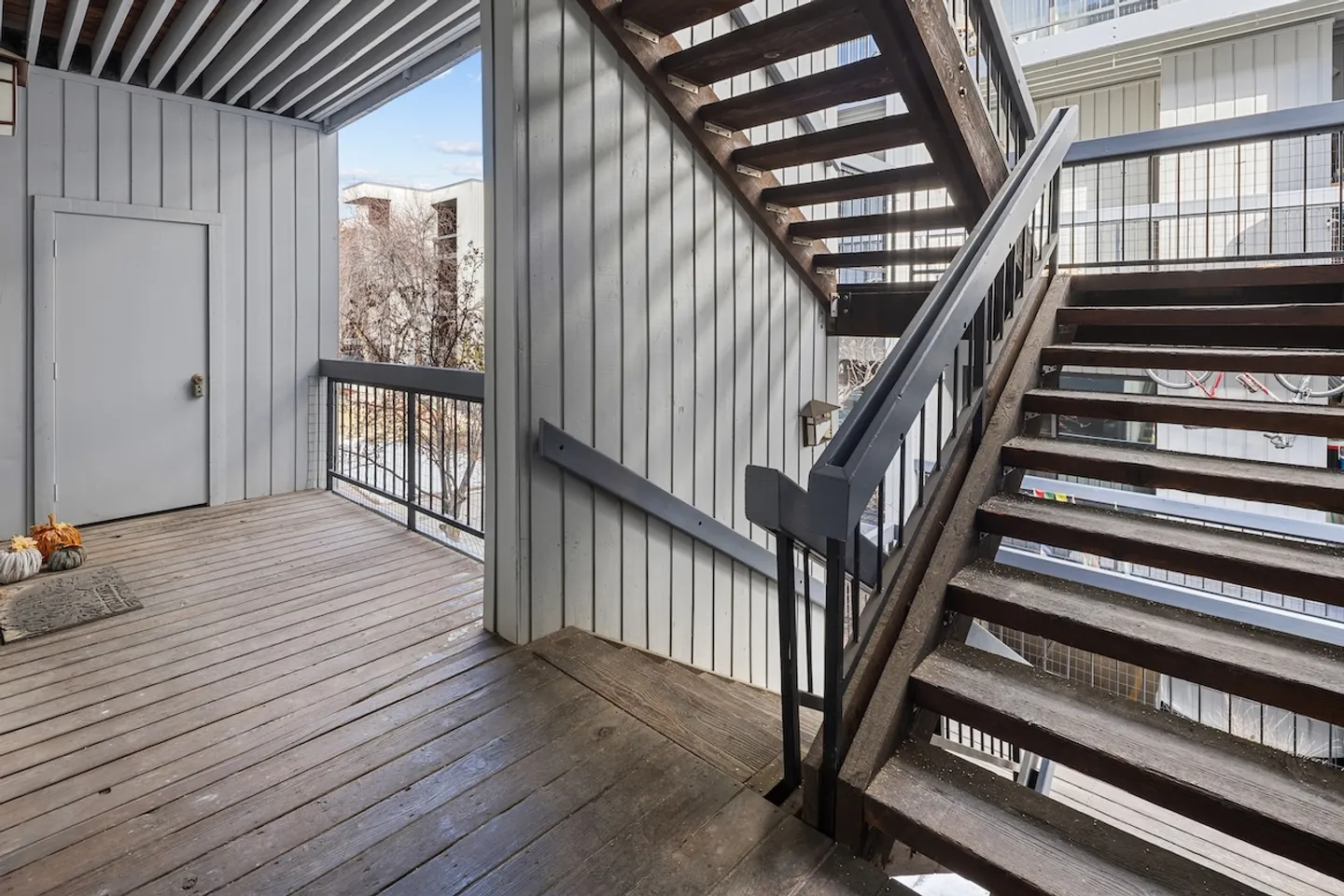 Exterior open-air landing and wooden staircase outside a residential entrance.