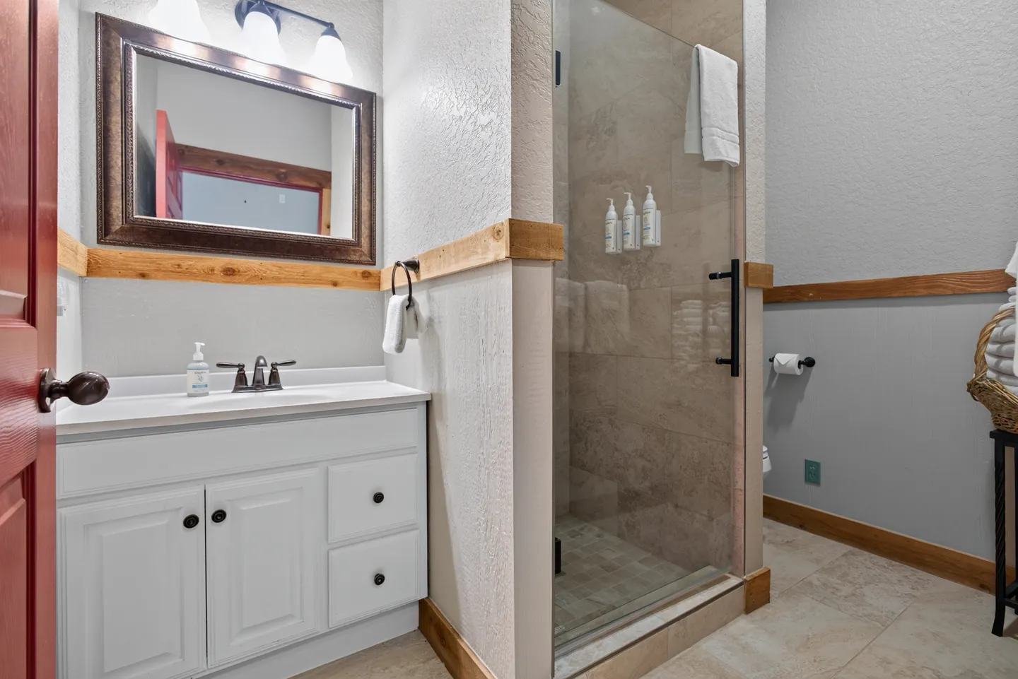 Bathroom with white vanity, framed mirror, and glass-enclosed walk-in shower.