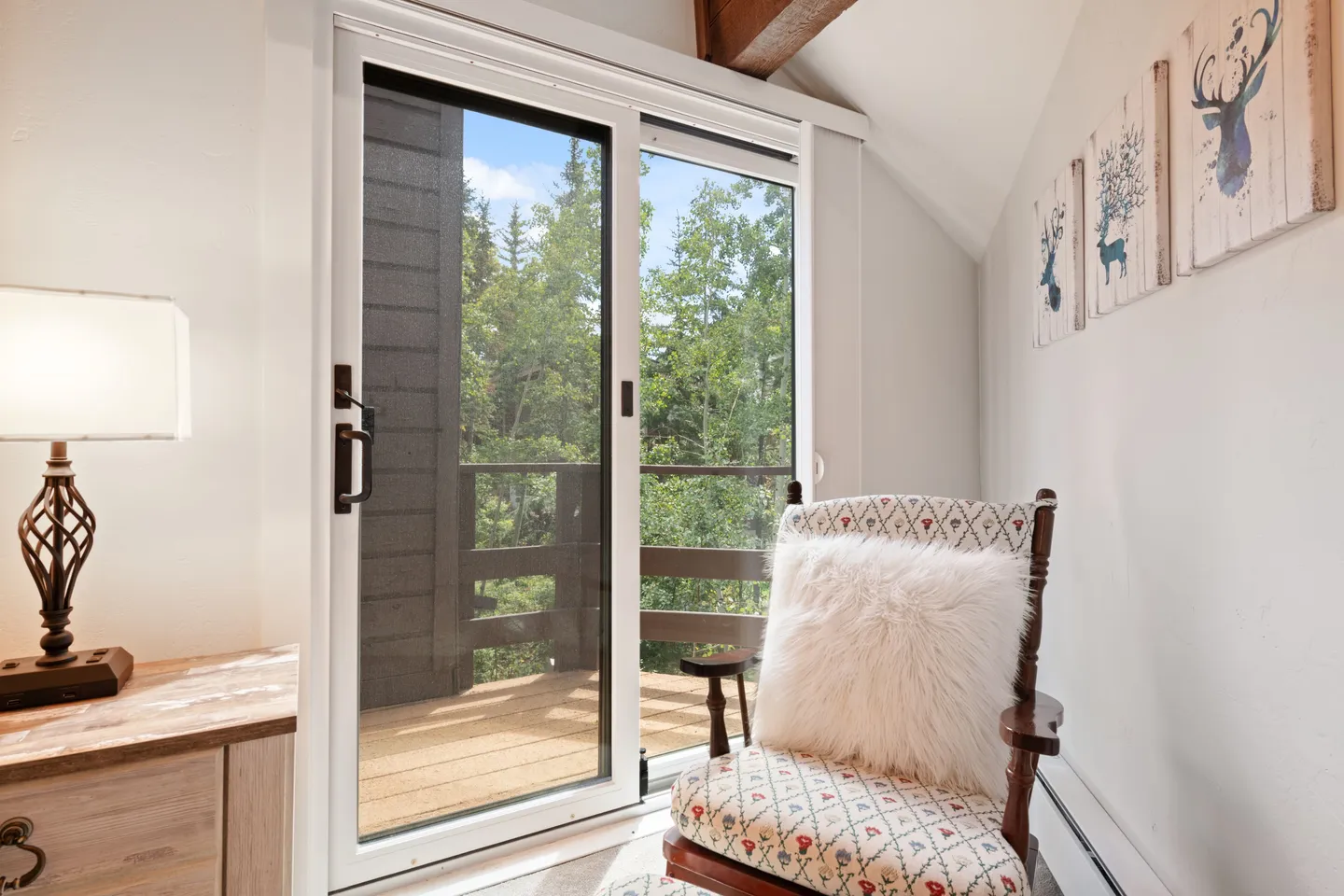 Sliding glass door leading to an outdoor balcony, with an armchair and bedside table in the foreground.