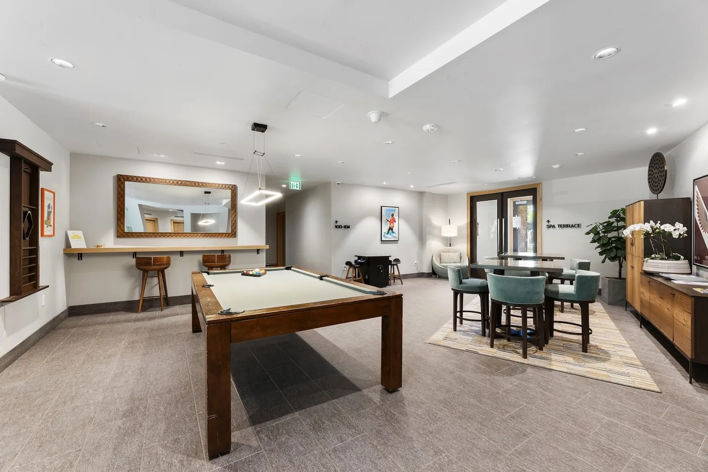 Game room featuring a wooden pool table, bar counter with stools, high-top seating table, and tiled flooring.
