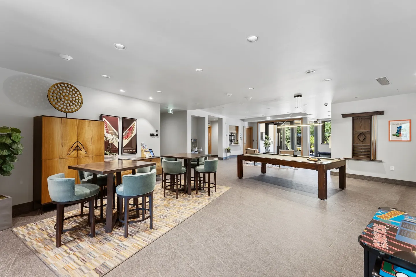 Spacious indoor game room and lounge featuring high-top tables with chairs, a pool table, and contemporary decor.