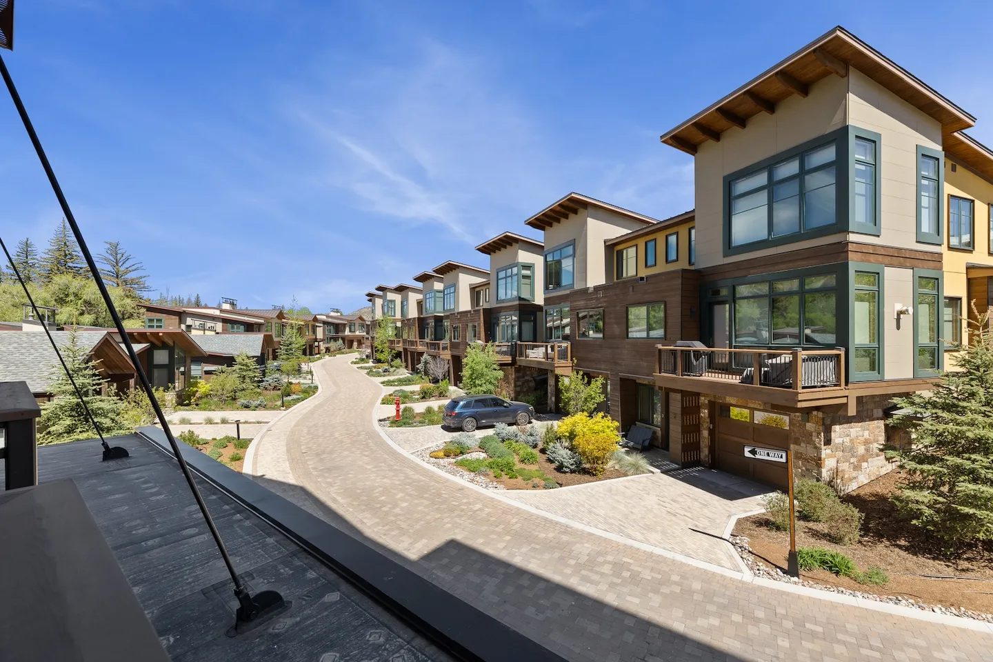 Elevated view overlooking a paved street lined with modern multi-story townhomes under a clear blue sky.