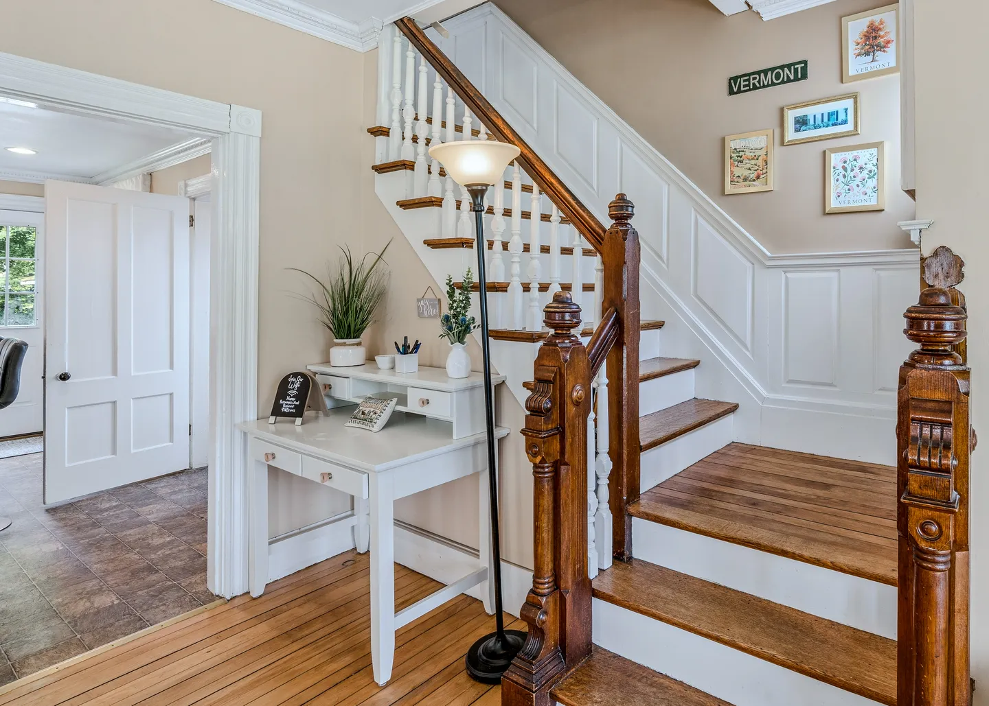 Staircase with wood treads and white risers next to a small white desk tucked in the nook beneath the stairs.