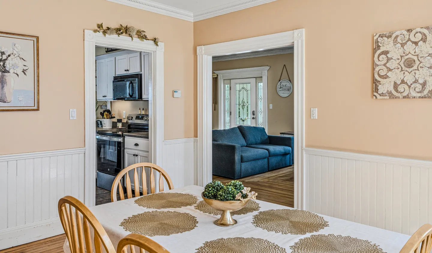 Dining area with a set table looking through doorways into the kitchen and living room.