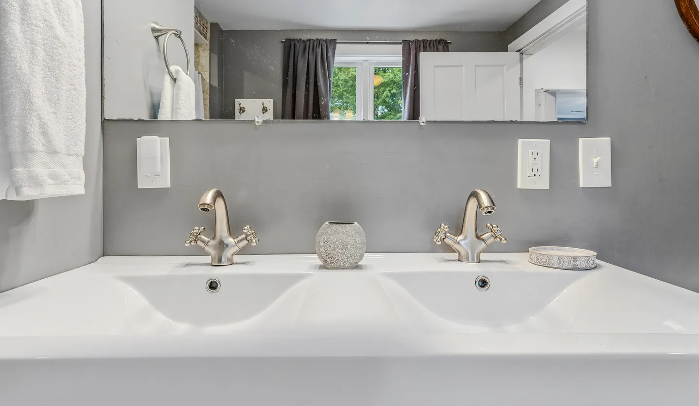 Close-up of a white double-basin vanity with brushed nickel faucets in a bathroom.