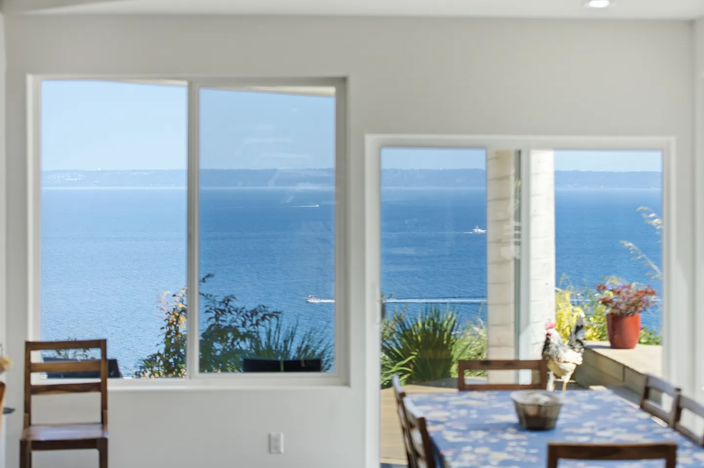 Large picture windows and sliding glass door inside a home looking out over blue open water with boats.