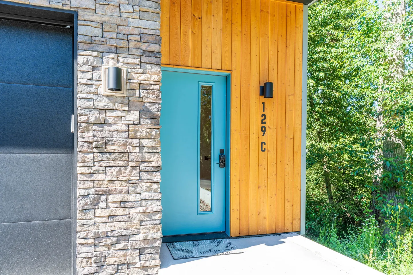 Exterior front entrance featuring a bright blue front door, stone veneer, and vertical wood siding.