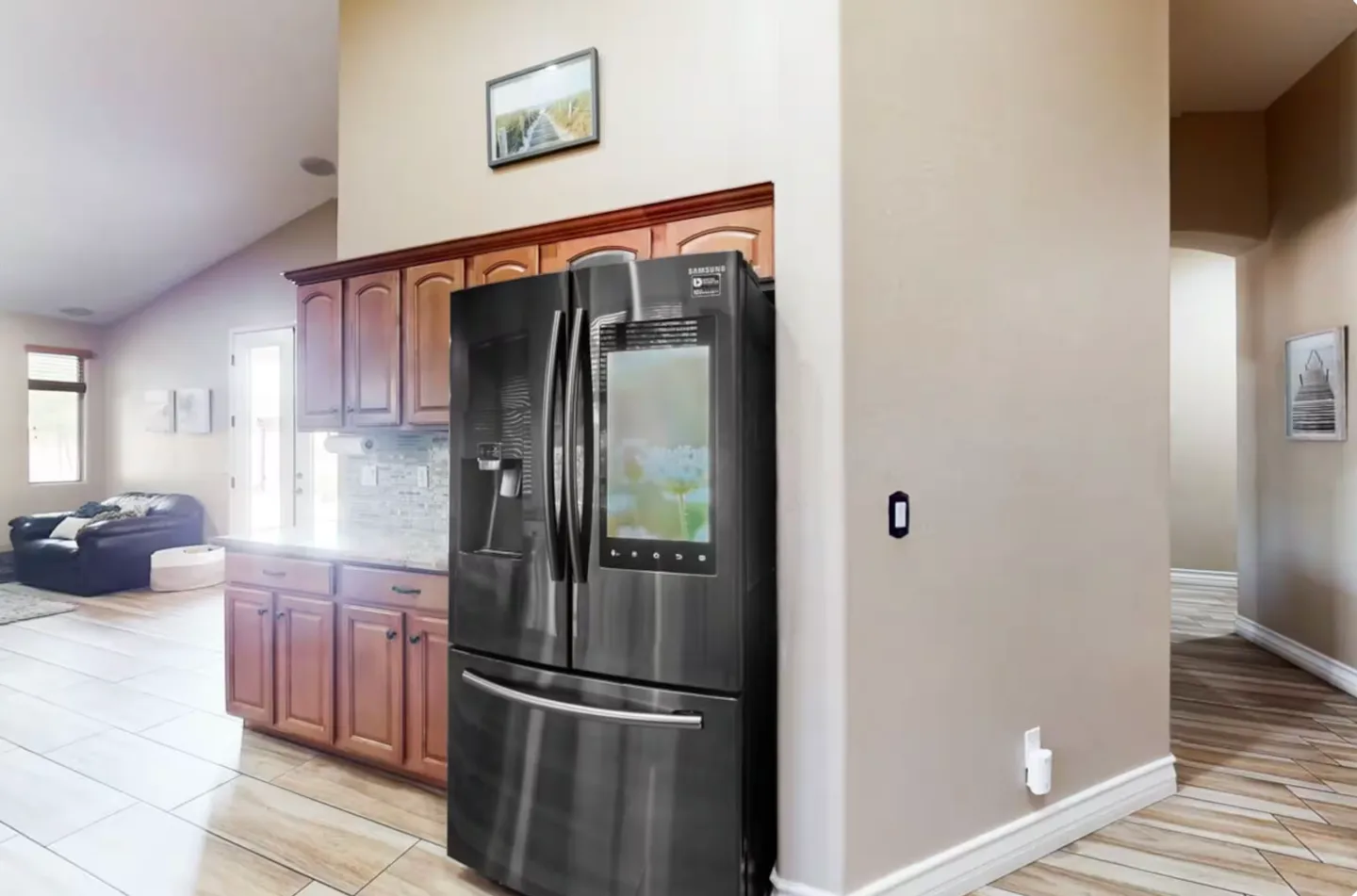 A modern dark stainless steel smart refrigerator with a built-in touchscreen in a kitchen nook.