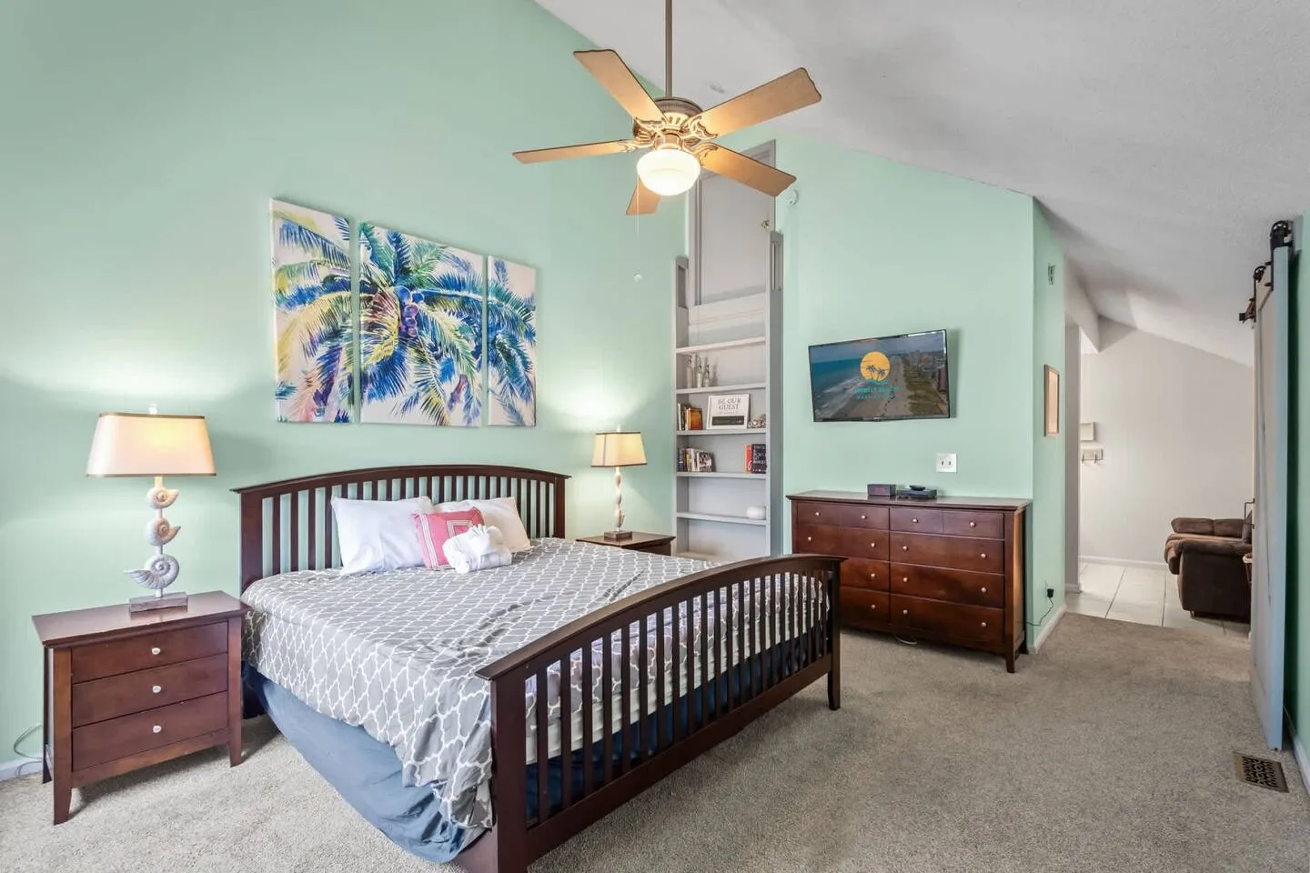 Bedroom with light green walls, a dark wood bed frame, matching nightstands, a dresser, and a ceiling fan.