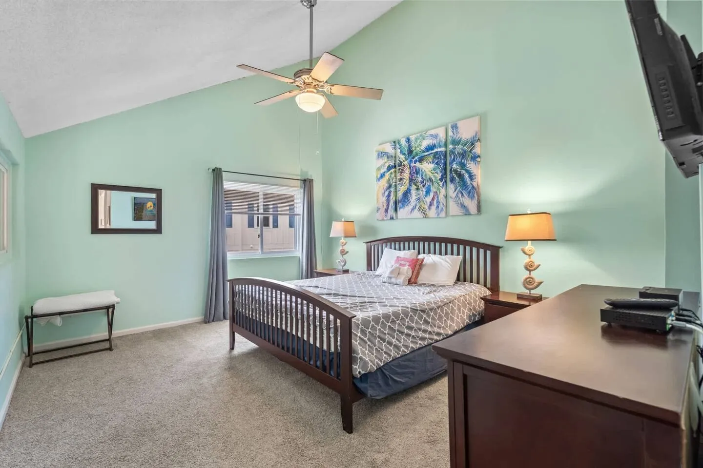 Bedroom with vaulted ceiling, light mint walls, dark wood bed frame, and carpeted floor.