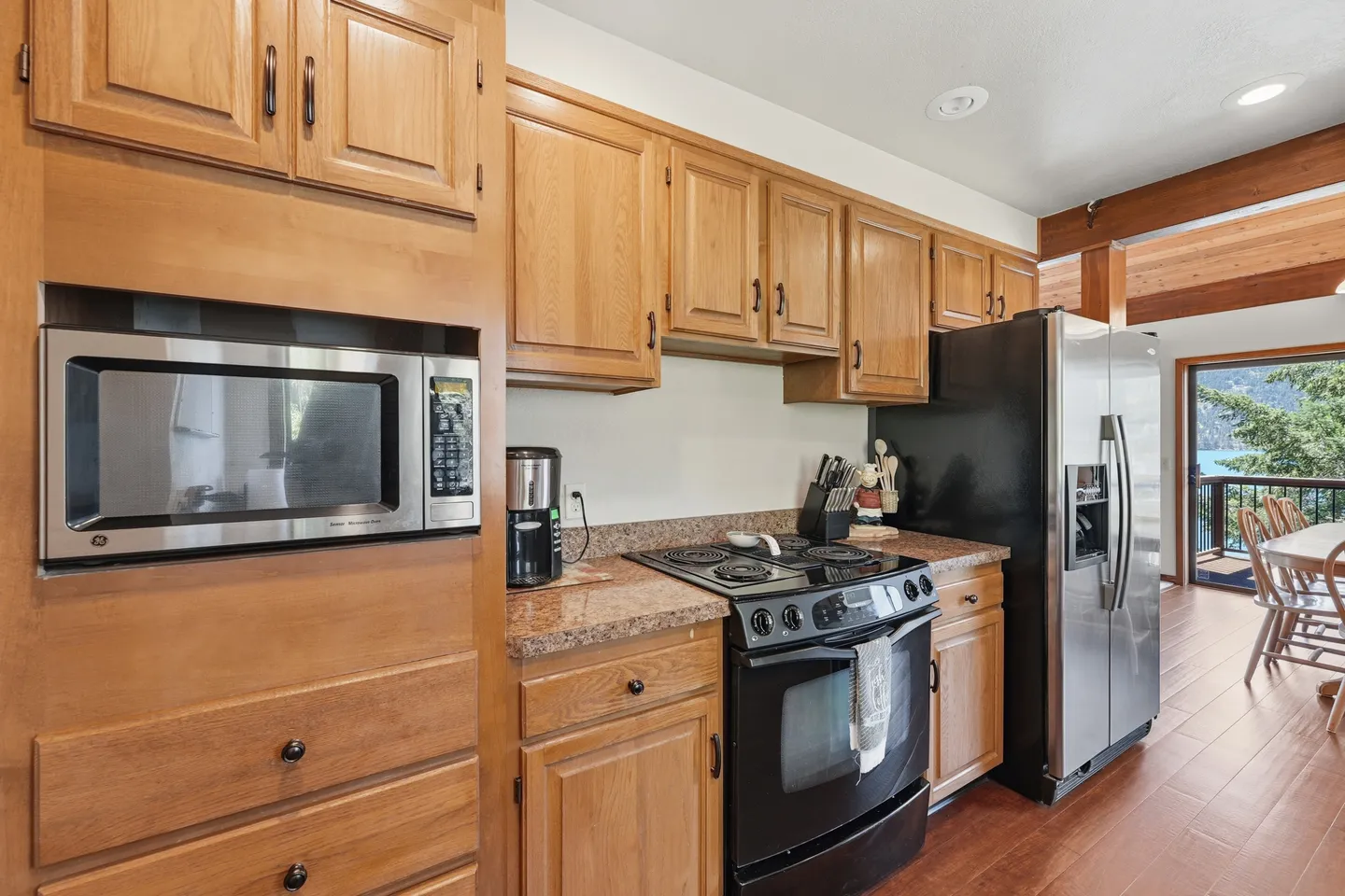 Kitchen with wooden cabinetry, a built-in microwave, electric stove, and stainless steel refrigerator.
