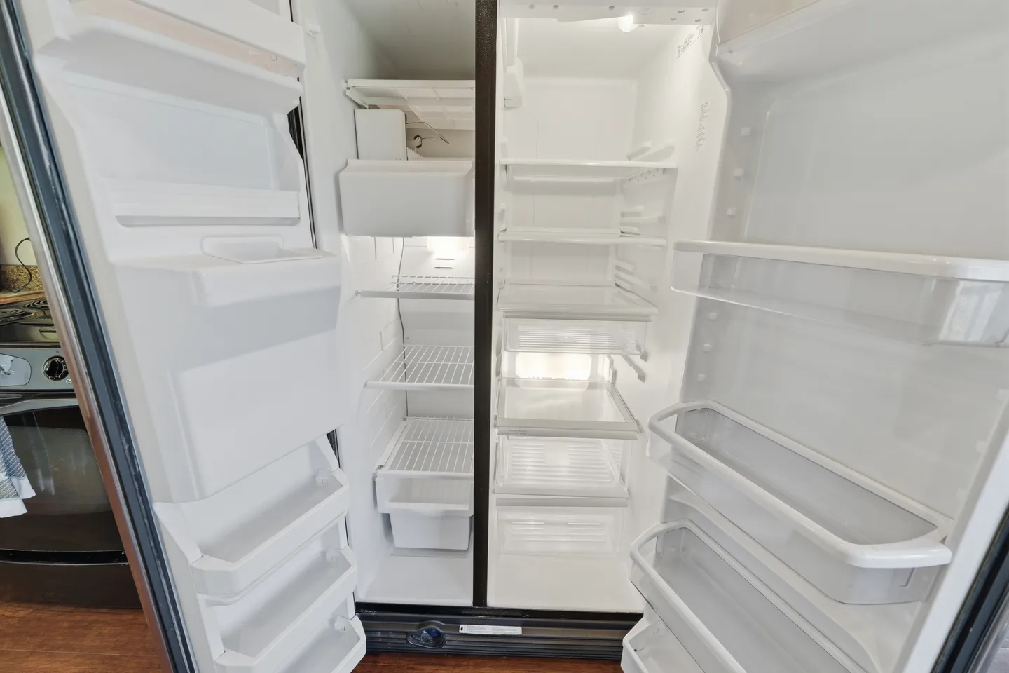 Open side-by-side refrigerator and freezer showing clean, empty interior shelves and door bins.