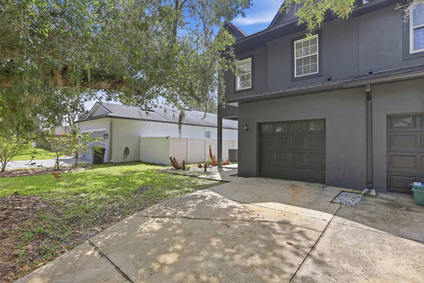 Exterior view of a dark gray two-story house with a concrete driveway and garage door.