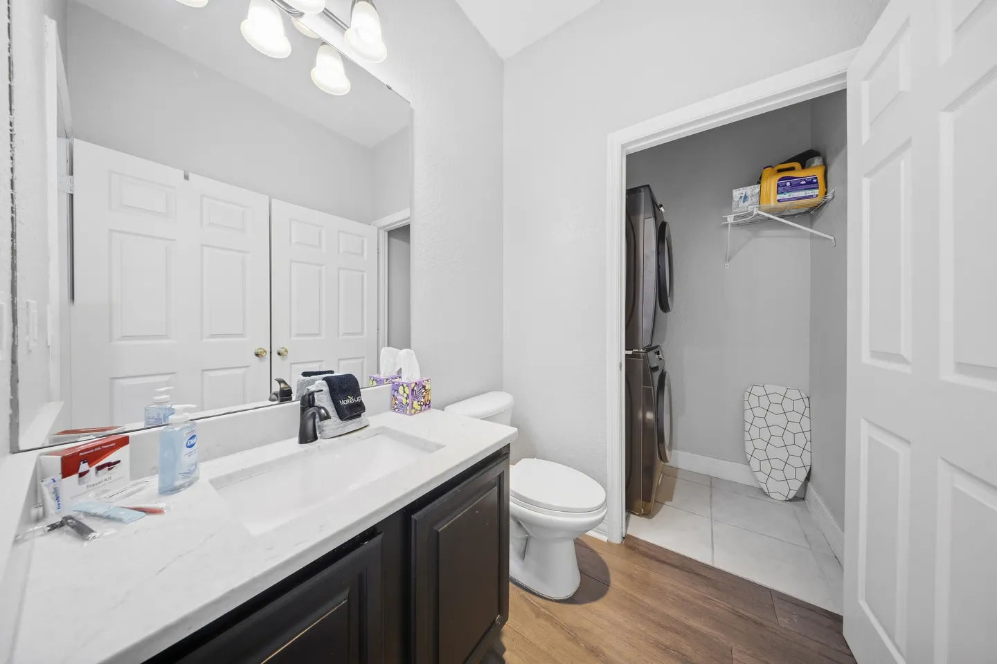Bathroom with vanity, toilet, and an open doorway leading to a laundry closet with stacked washer and dryer.
