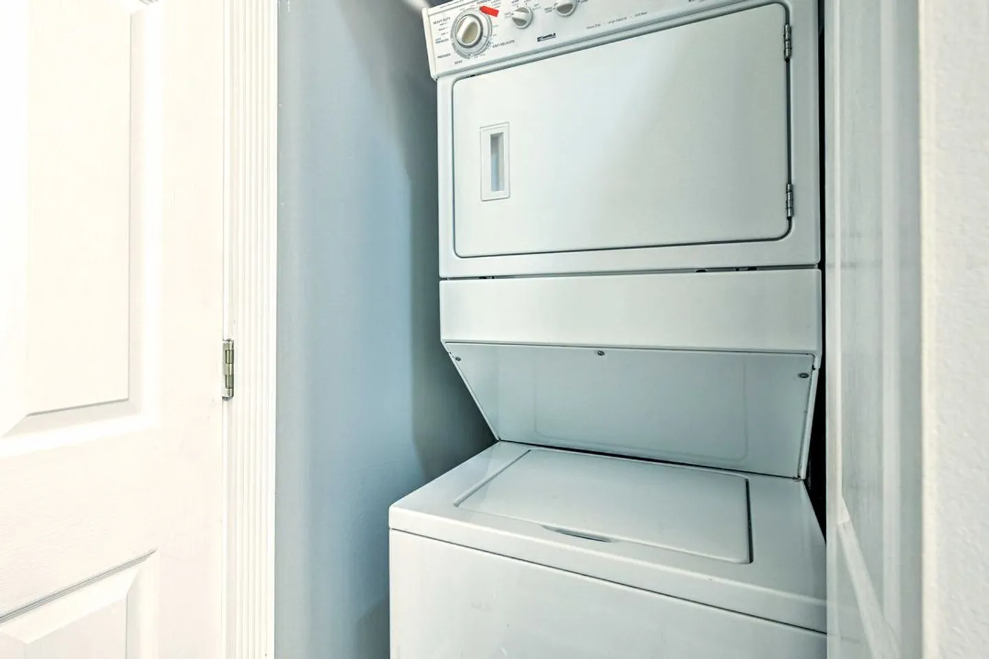 Stacked white washer and dryer unit inside a compact laundry closet.