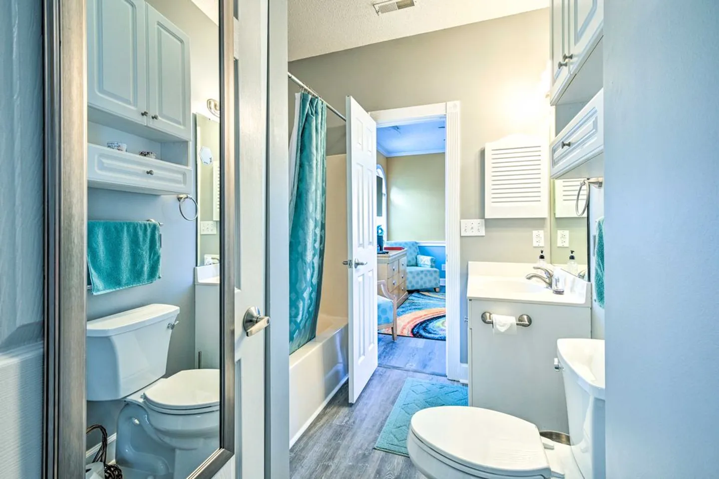 Bathroom with white vanity, toilet, and shower curtain, reflected in a framed mirror.