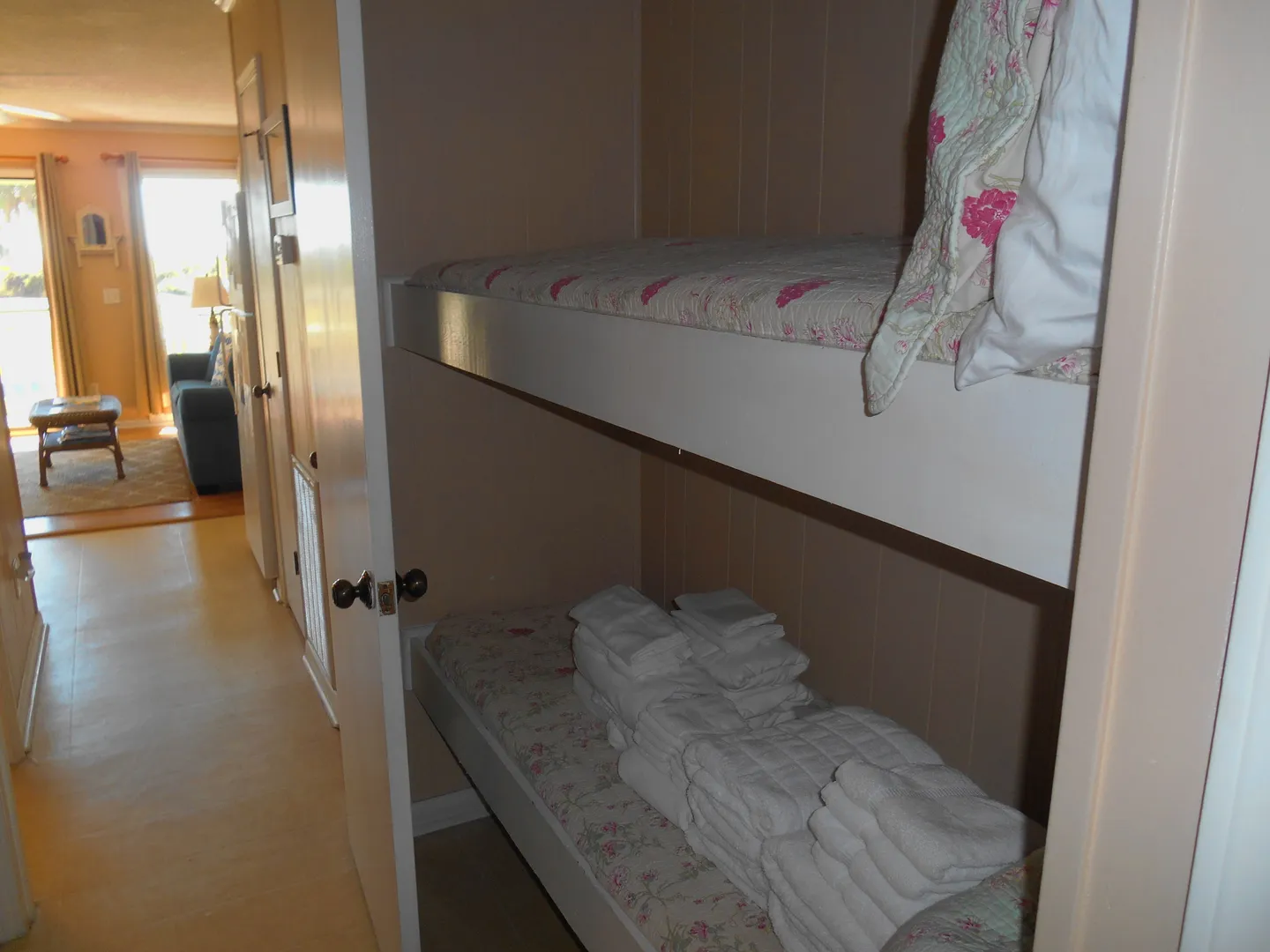 Built-in bunk beds tucked into a hallway alcove with stacked white towels on the lower bunk.