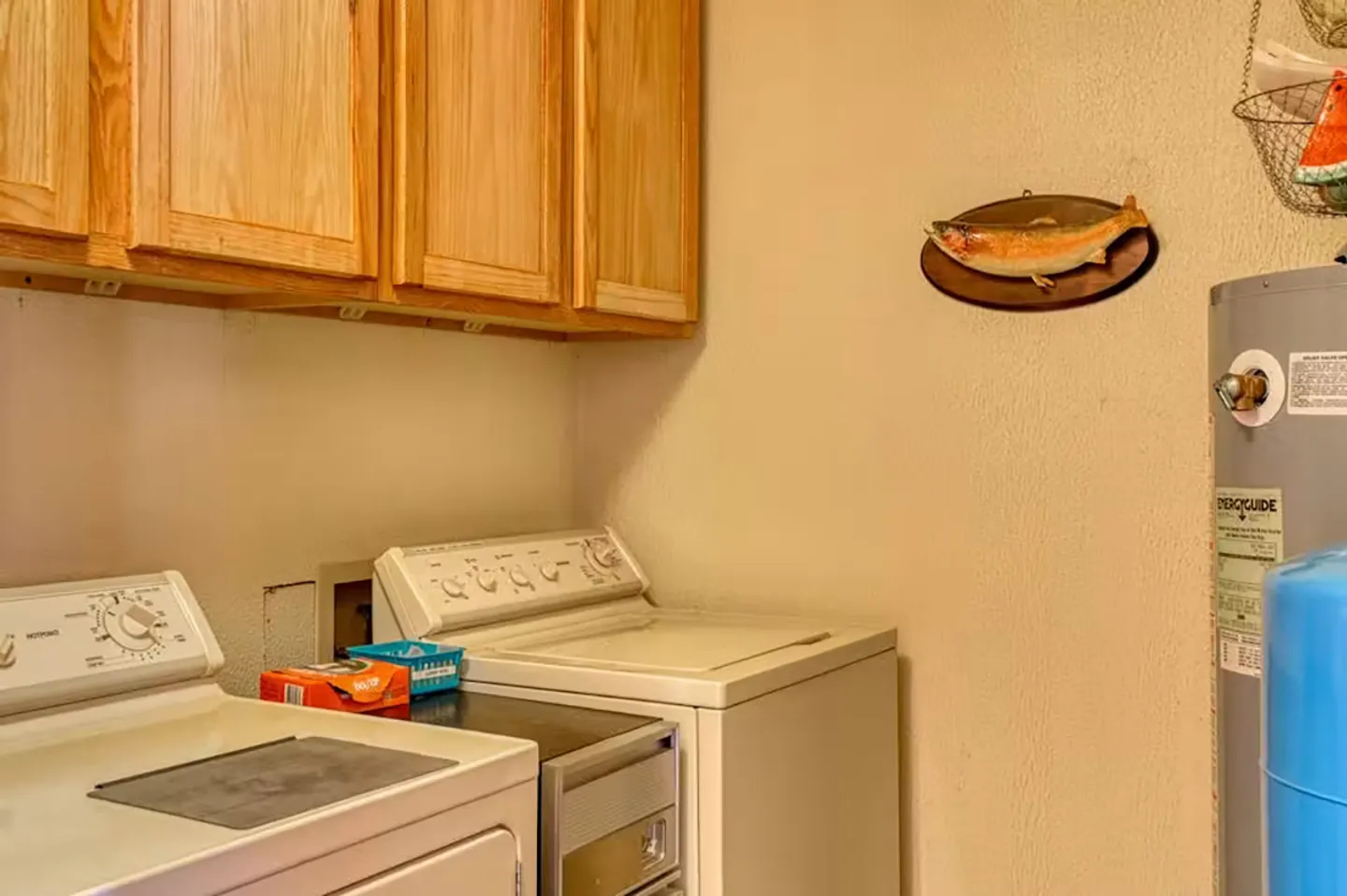 A laundry room area with a white washer and dryer beneath wooden cabinets, with a water heater on the right.