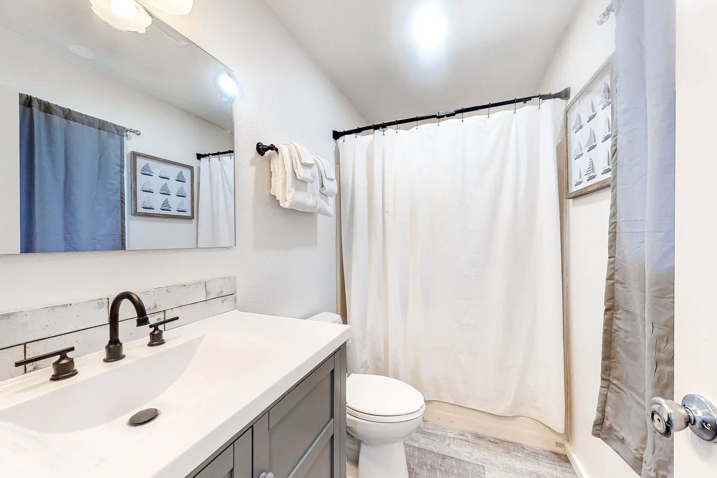 Bathroom with vanity, toilet, and shower covered by a white curtain.