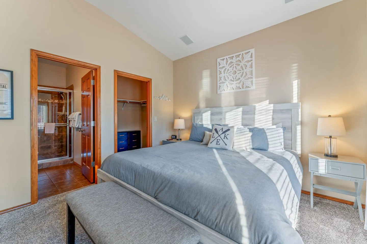 Bedroom with a large bed, nightstands with lamps, a closet, and an open doorway leading to an en-suite bathroom.