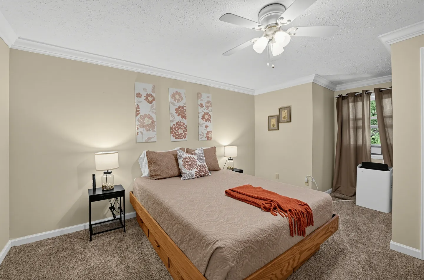 Bedroom featuring a wooden platform bed with drawers, carpeted floor, ceiling fan, and framed art on neutral walls.