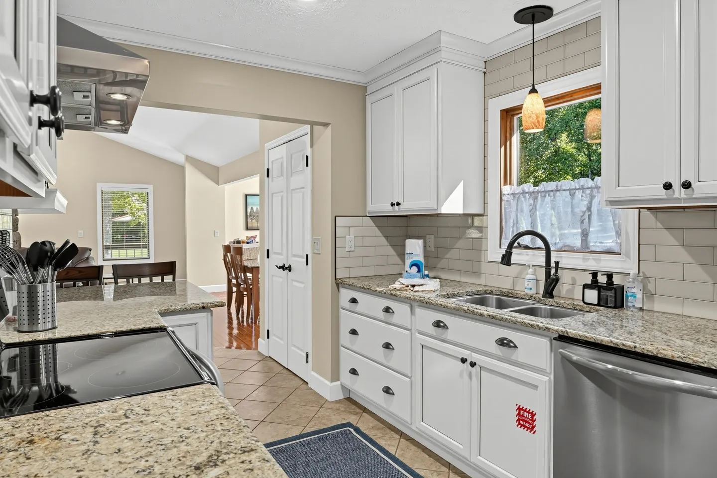 Kitchen with white cabinetry, granite-style countertops, stainless steel appliances, and a window above a double-basin sink.