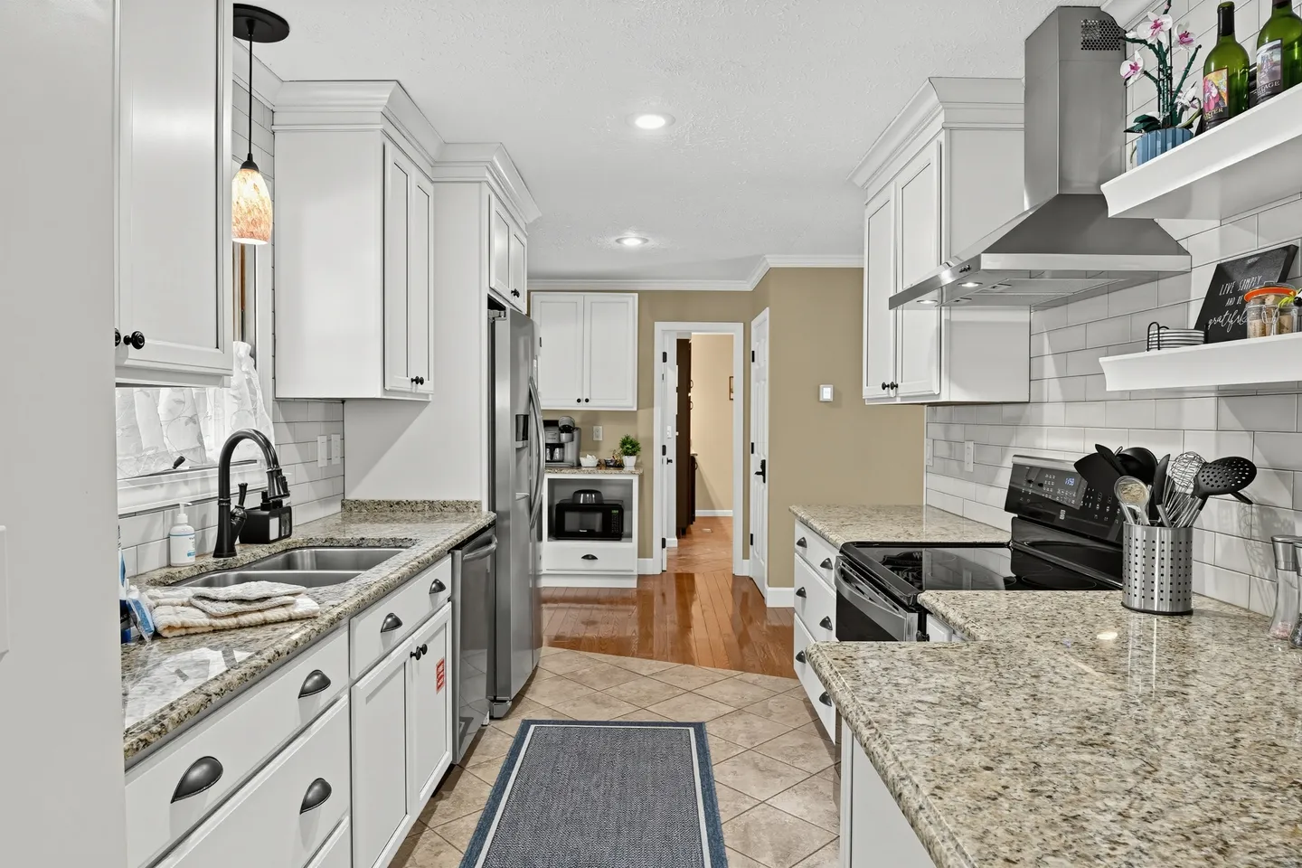 Modern kitchen with white shaker cabinets, speckled granite countertops, and stainless steel appliances.