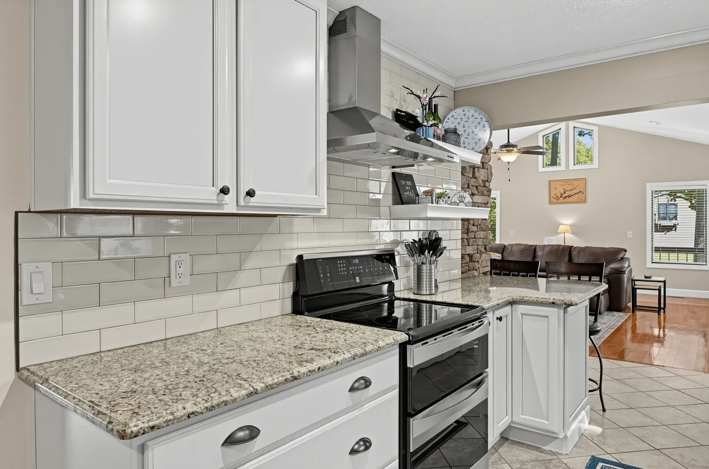 Kitchen counter with white cabinets, speckled stone countertops, a subway tile backsplash, and a black and stainless steel range.