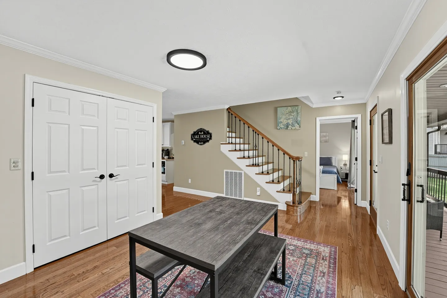 Open indoor entryway and dining space with wood floors, a table with bench seating, a staircase, and double closet doors.