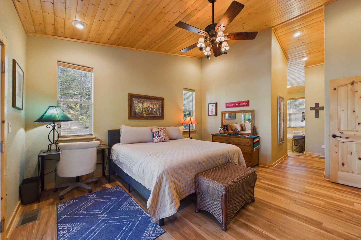 Bedroom with wood-paneled ceiling, large bed, desk, and dresser.