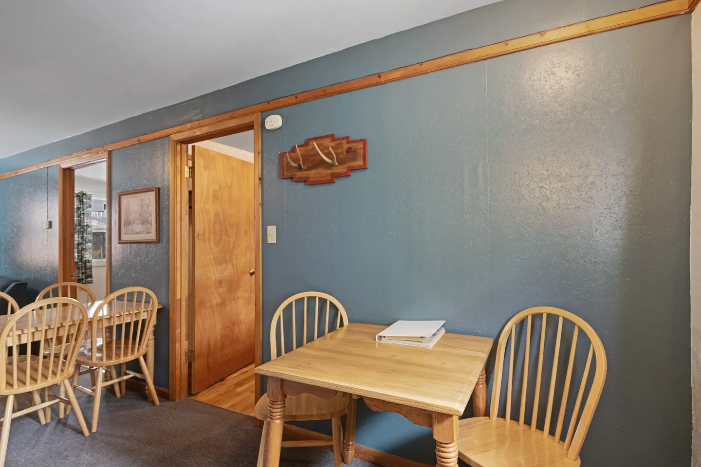 Indoor dining space with teal painted walls, wood trim, and light wood tables and chairs.
