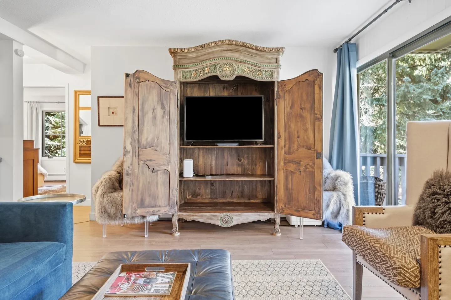 Living room featuring a television enclosed in an ornate wooden armoire with open cabinet doors.