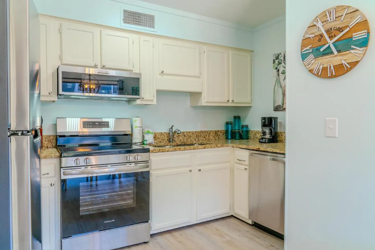 Kitchen with white cabinetry, speckled granite-look countertops, and stainless steel appliances.