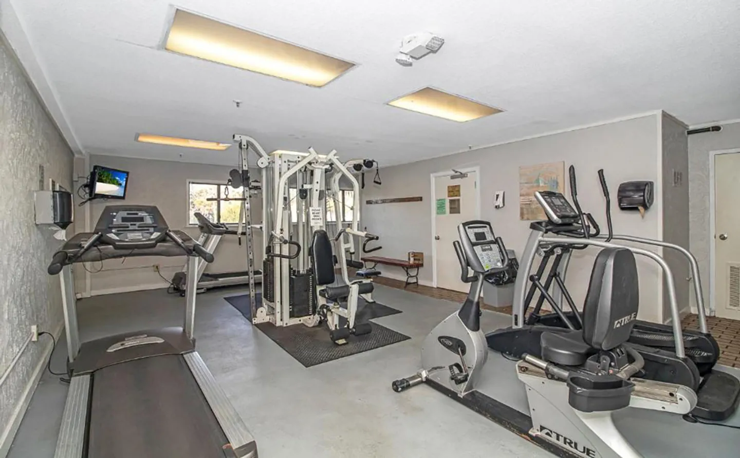 Indoor fitness room featuring treadmills, exercise bikes, and a multi-station weight machine.