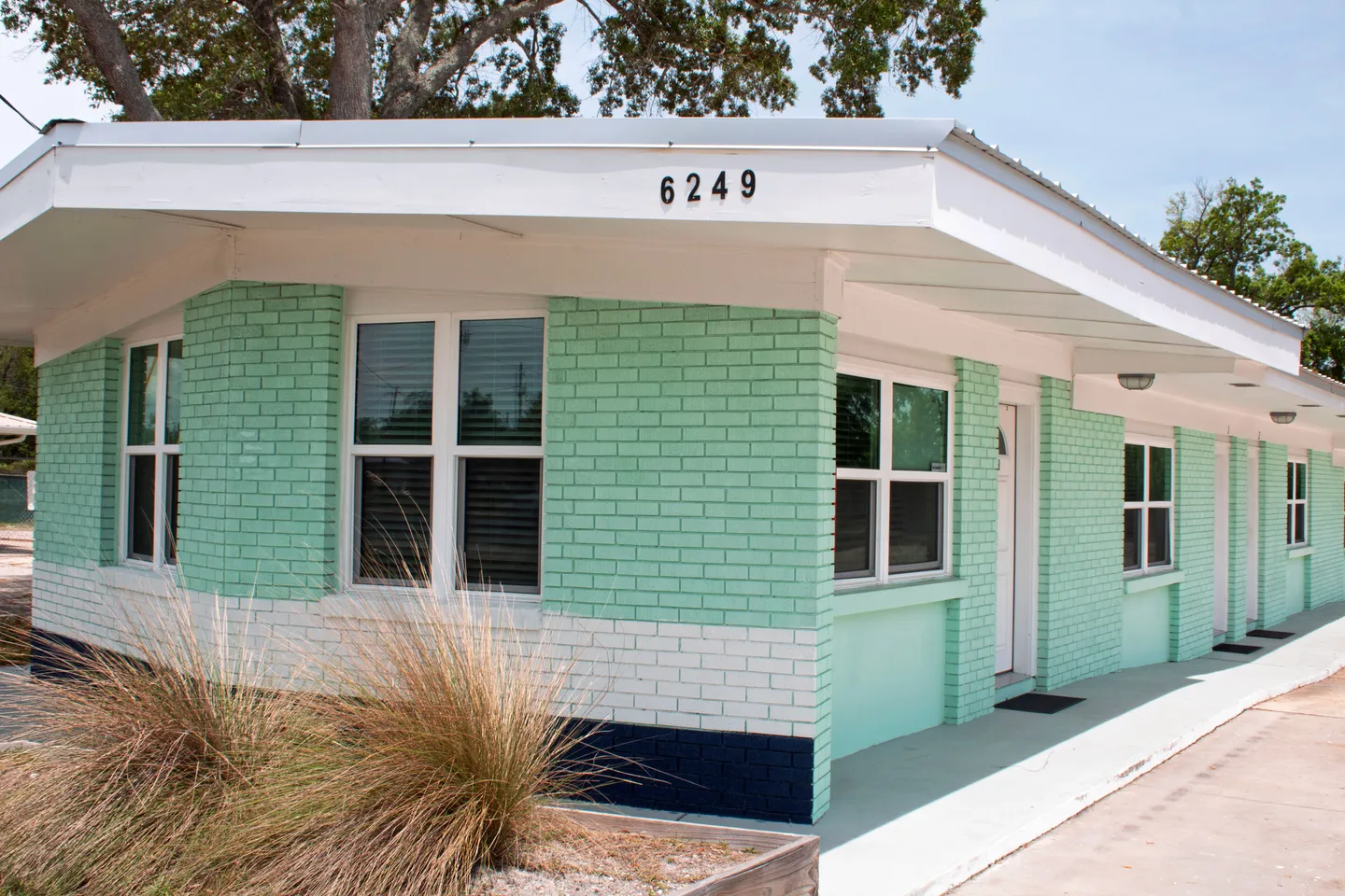 Exterior of a painted brick building with mint green and white walls under a clear sky.