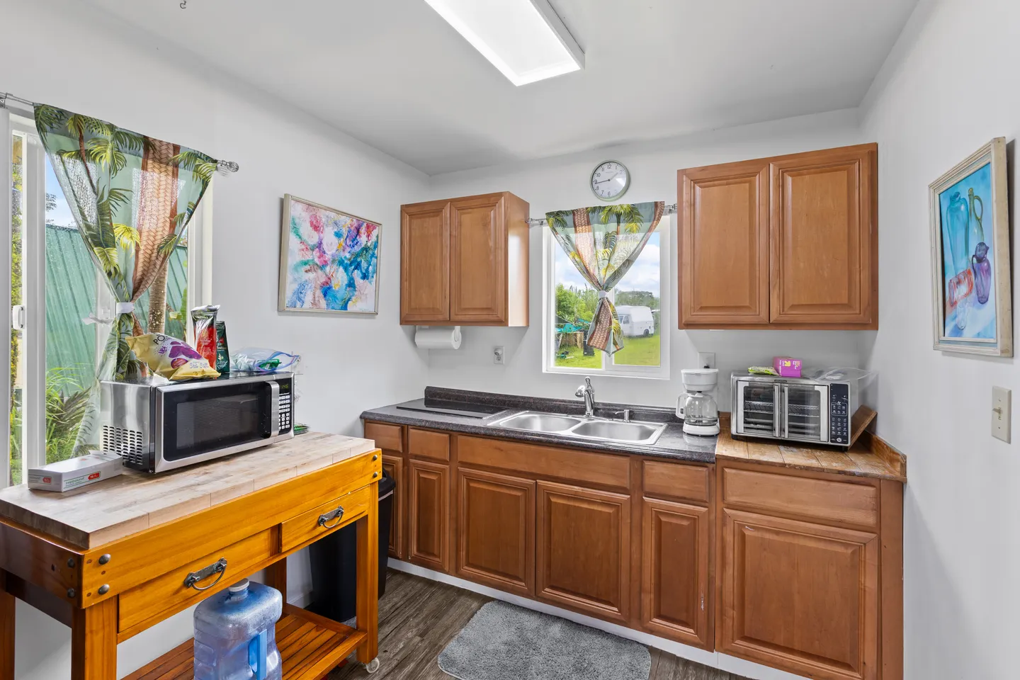 Kitchen featuring wooden cabinets, a double sink under a window, countertop appliances, and a butcher block island cart.