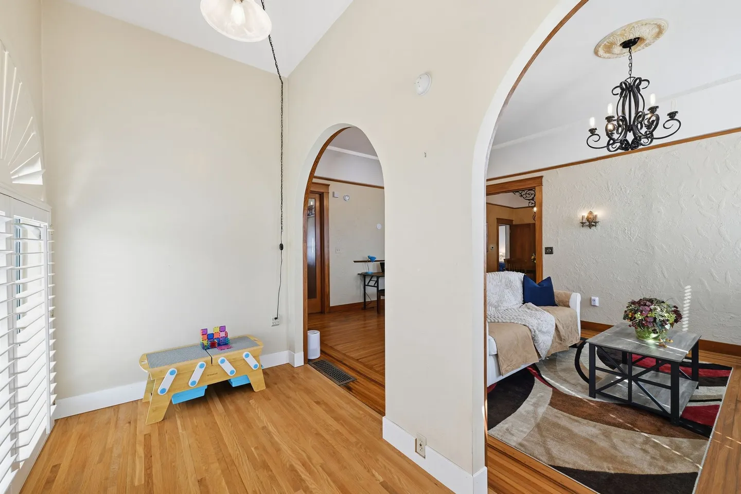 Interior view showing arched doorways leading from a light-colored room with wood floors to an adjoining living area.