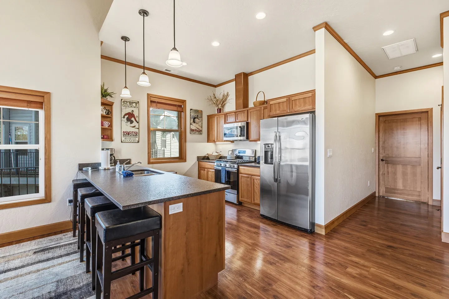 Kitchen with wood-grain cabinets, dark island countertop with bar seating, and stainless steel appliances.