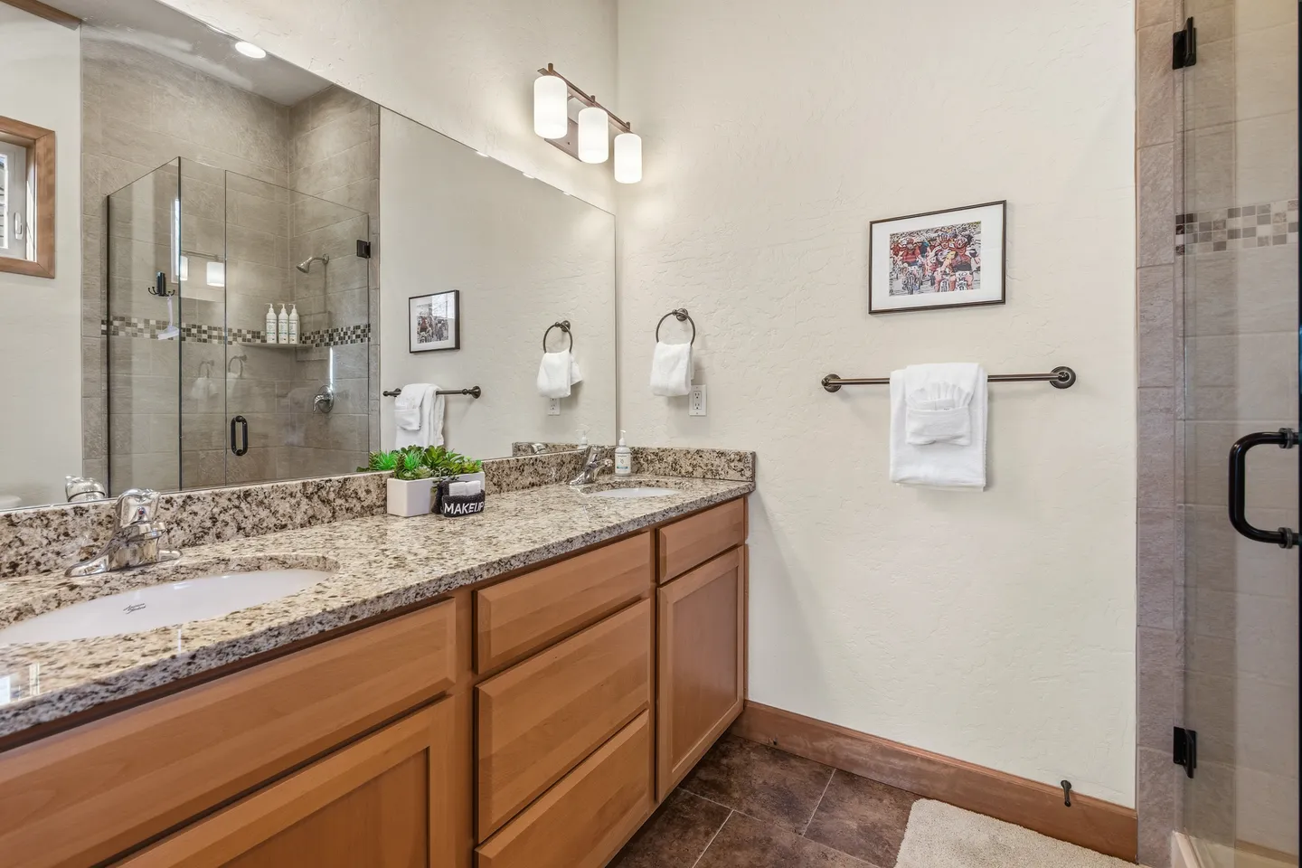 Bathroom with a double-sink granite vanity, large mirror, and glass-enclosed walk-in shower.
