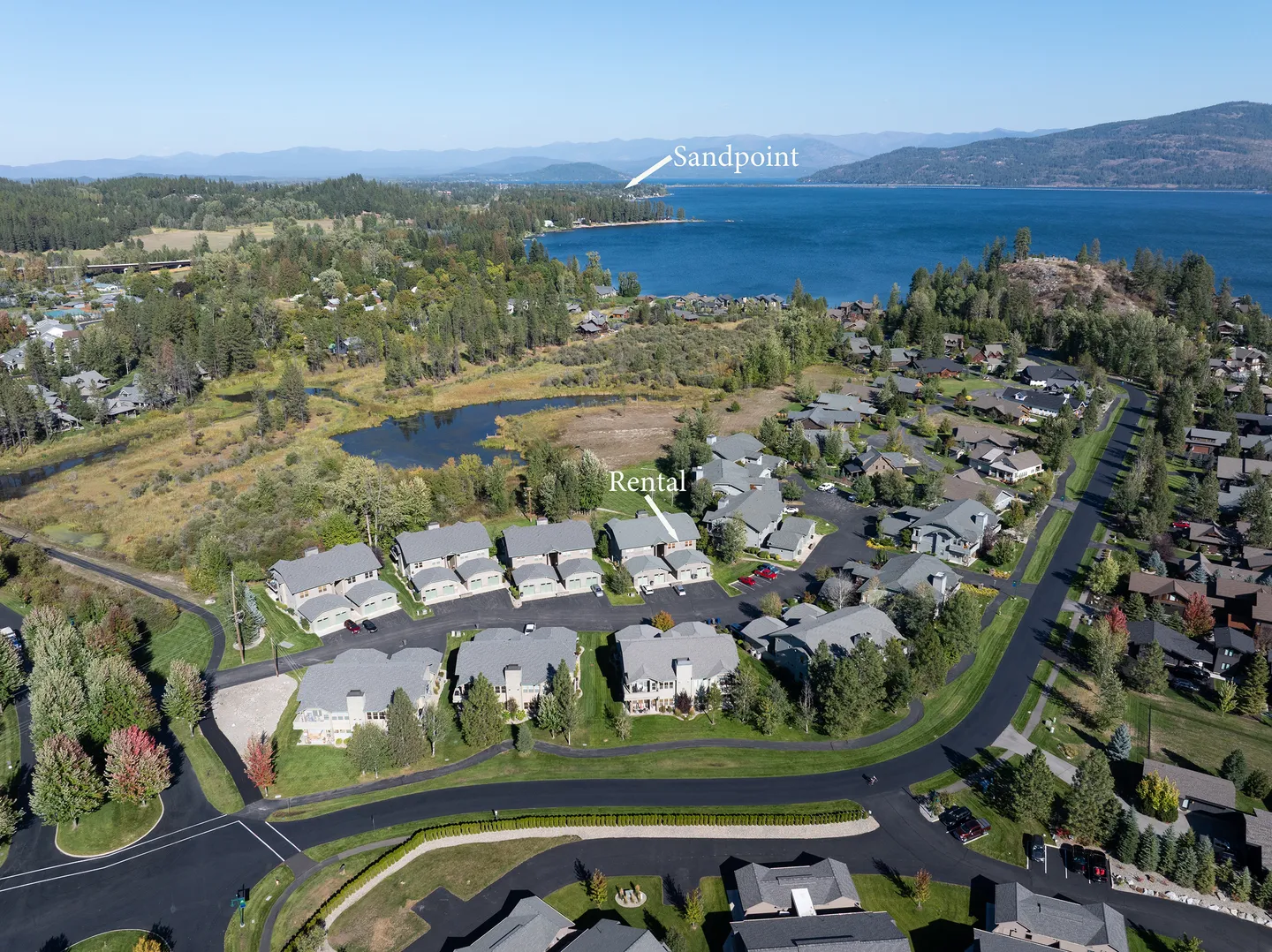 Aerial view showing residential townhomes situated near a large lake with distant mountains.